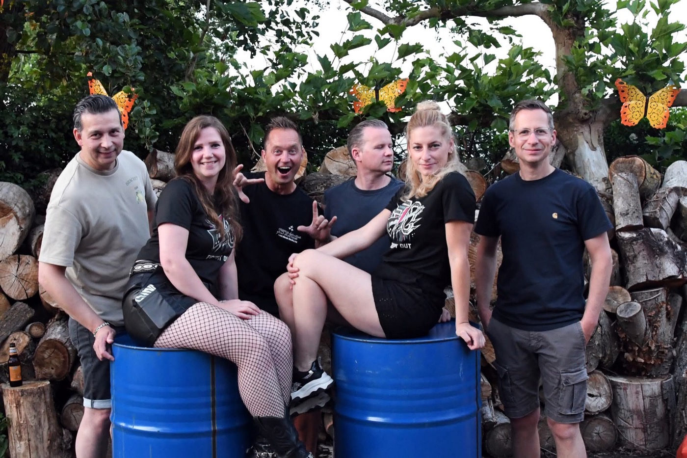 De crew poseert op blauwe tonnen voor een houtstapel
