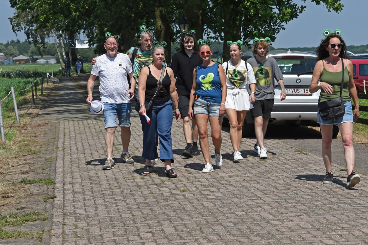 Bezoekers met kikker-haarbanden lopen naar het festival